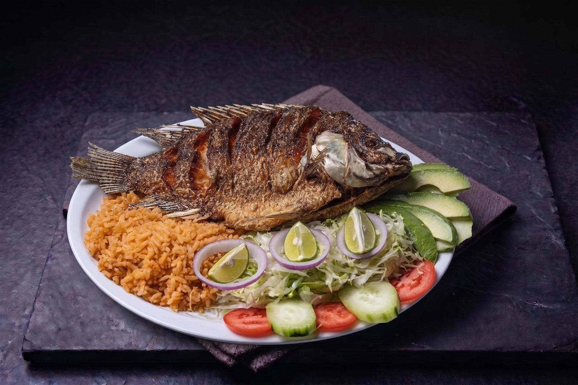 Mojarra frita dorada servida con arroz, ensalada y aguacate