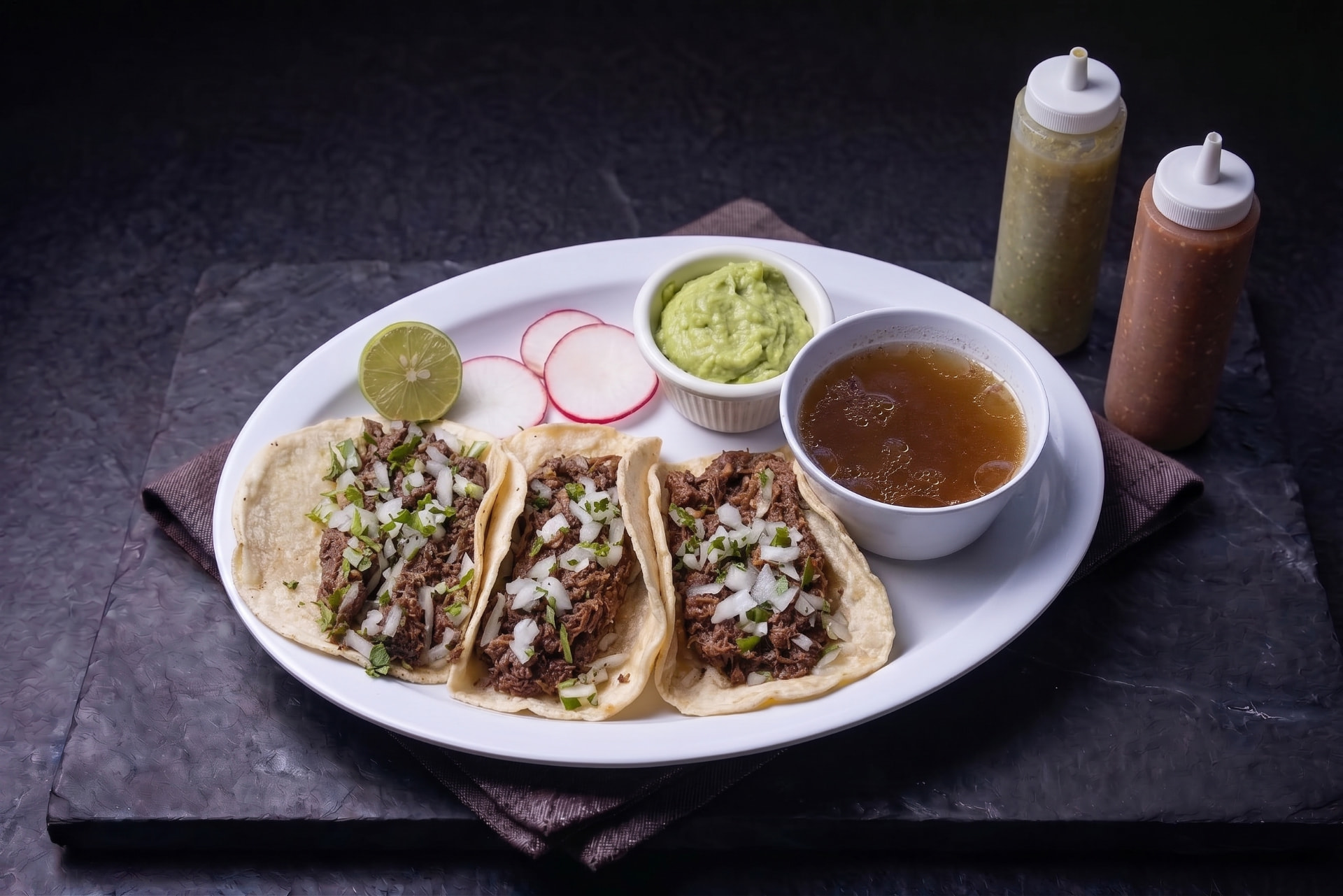 Tacos de cabeza con cilantro, cebolla, guacamole, salsa y consomé